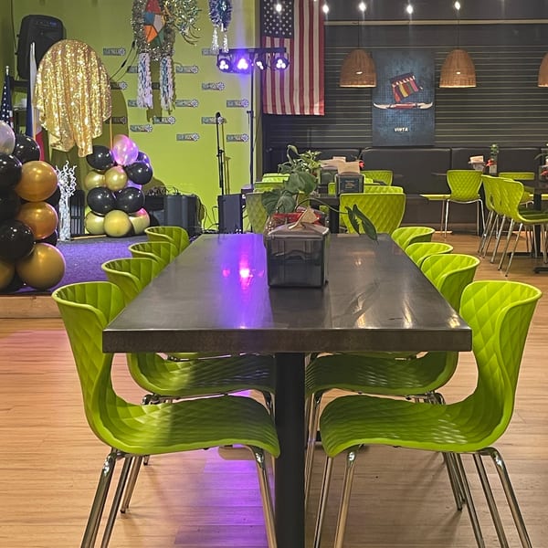 A long table with bright green chairs in a restaurant with festive decorations and an American flag.