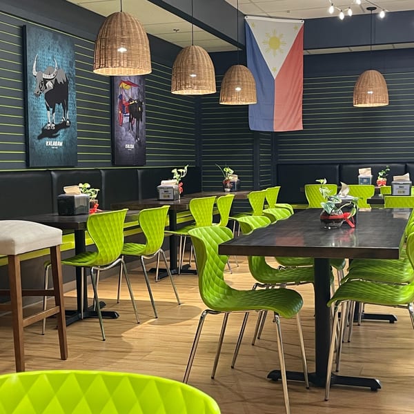 Maemax Market's dining area with dark tables, bright green chairs, and Filipino-themed decor.