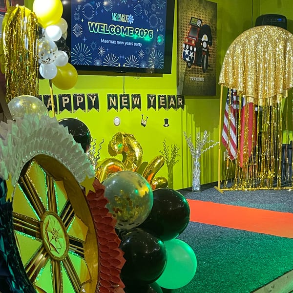 Maemax Market's New Year's party decorations with balloons, banners, and a "Welcome 2026" screen.