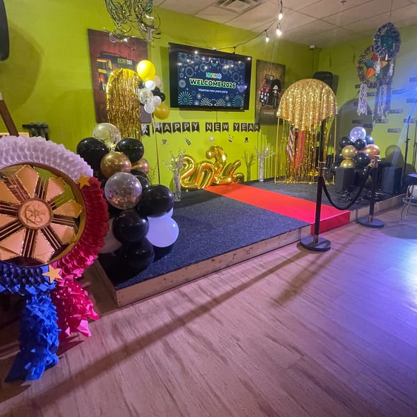 New Year's Eve decorations at Maemax Market, featuring a stage with a red carpet, balloons, and a TV screen.