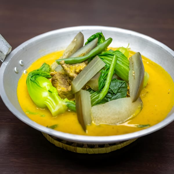 Filipino Kare-Kare with meat, bok choy, green beans, and eggplant in a rich peanut sauce.