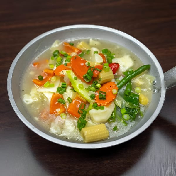 Filipino chop suey with carrots, cabbage, green beans, and baby corn in a metal pan.