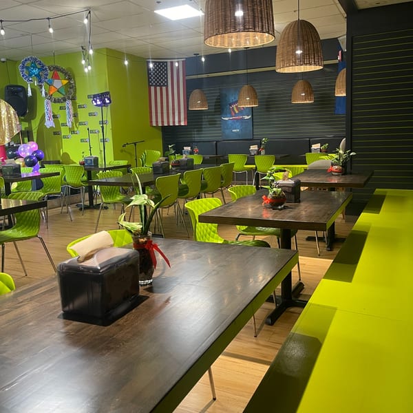 Maemax Market's dining area with lime green chairs and dark tables, decorated with Filipino parols and an American flag.